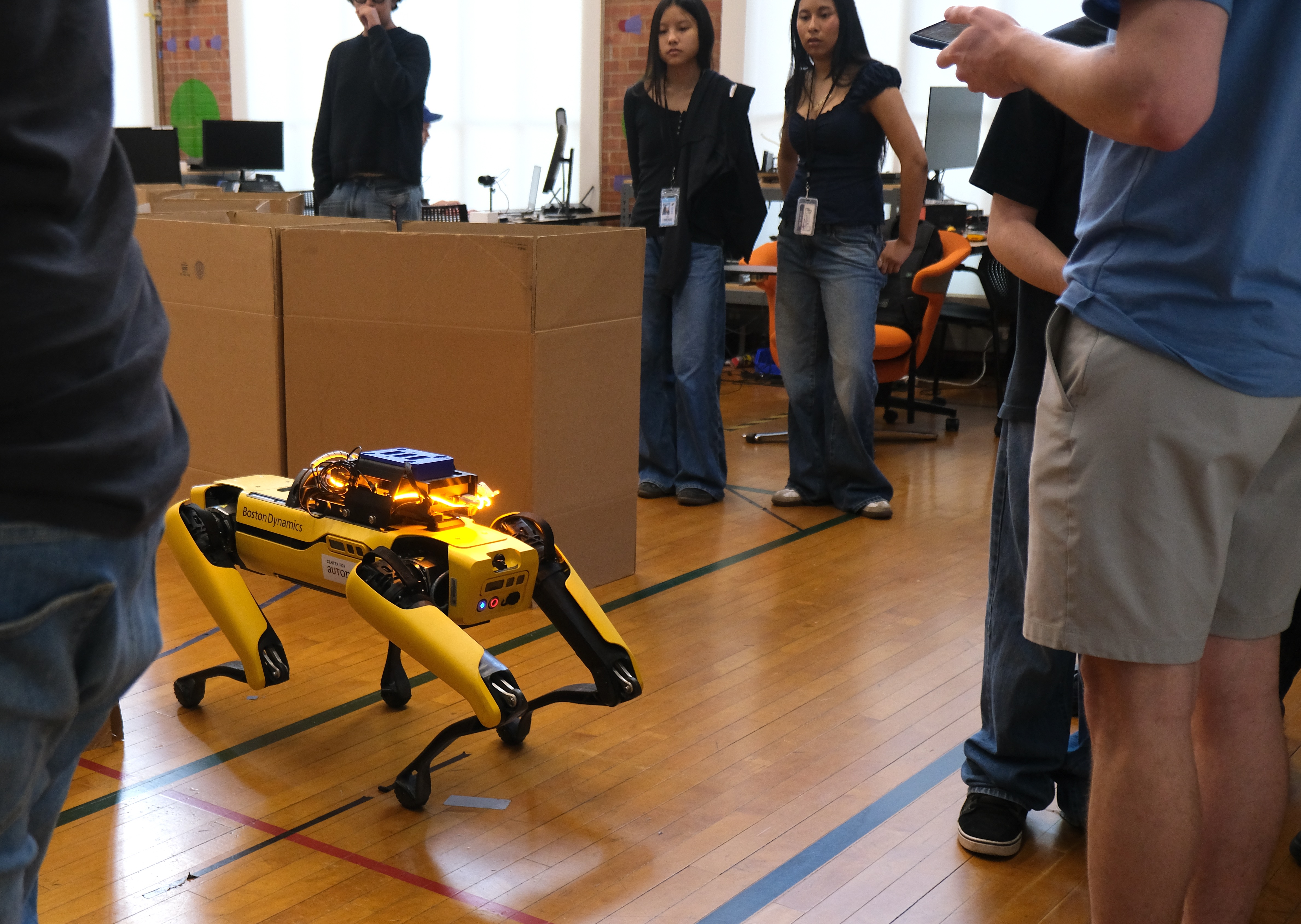 A quadruped robot navigates an obstacle course during the hands-on robot demos, where students take turns guiding robots with remote controls. Credit: Tai Cerulli/Oden Institute